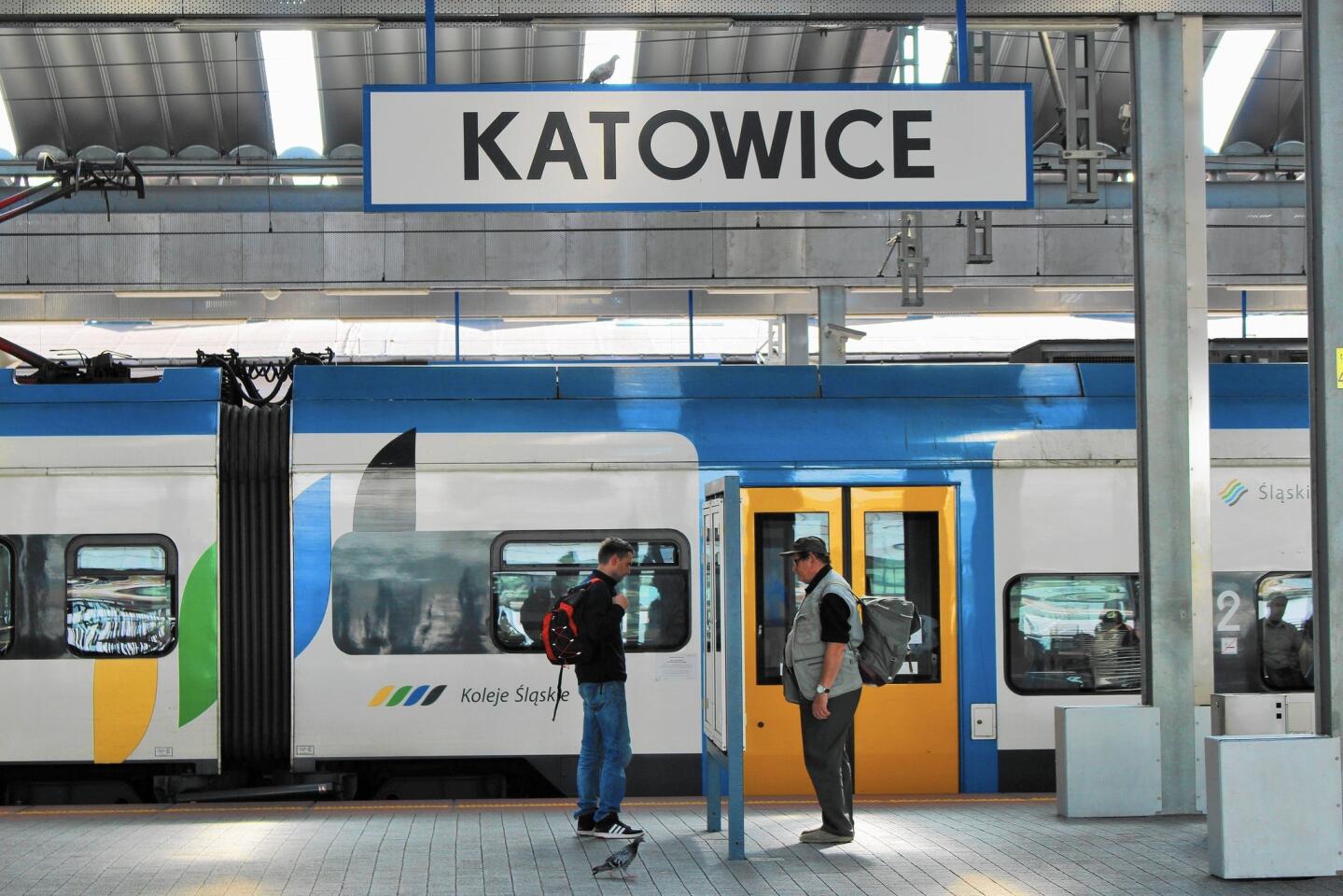 Two men and a pigeon examine timetables at the station in Katowice, connection point for the train to Wroclaw.
