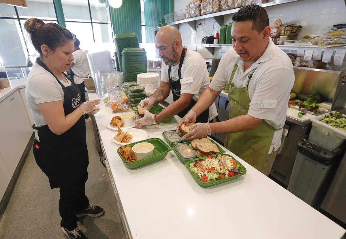 Employee Monica Rodriquez waits as Martin Andrade and Joel Ramirez build sandwiches and salads at Jan's Health Bar.