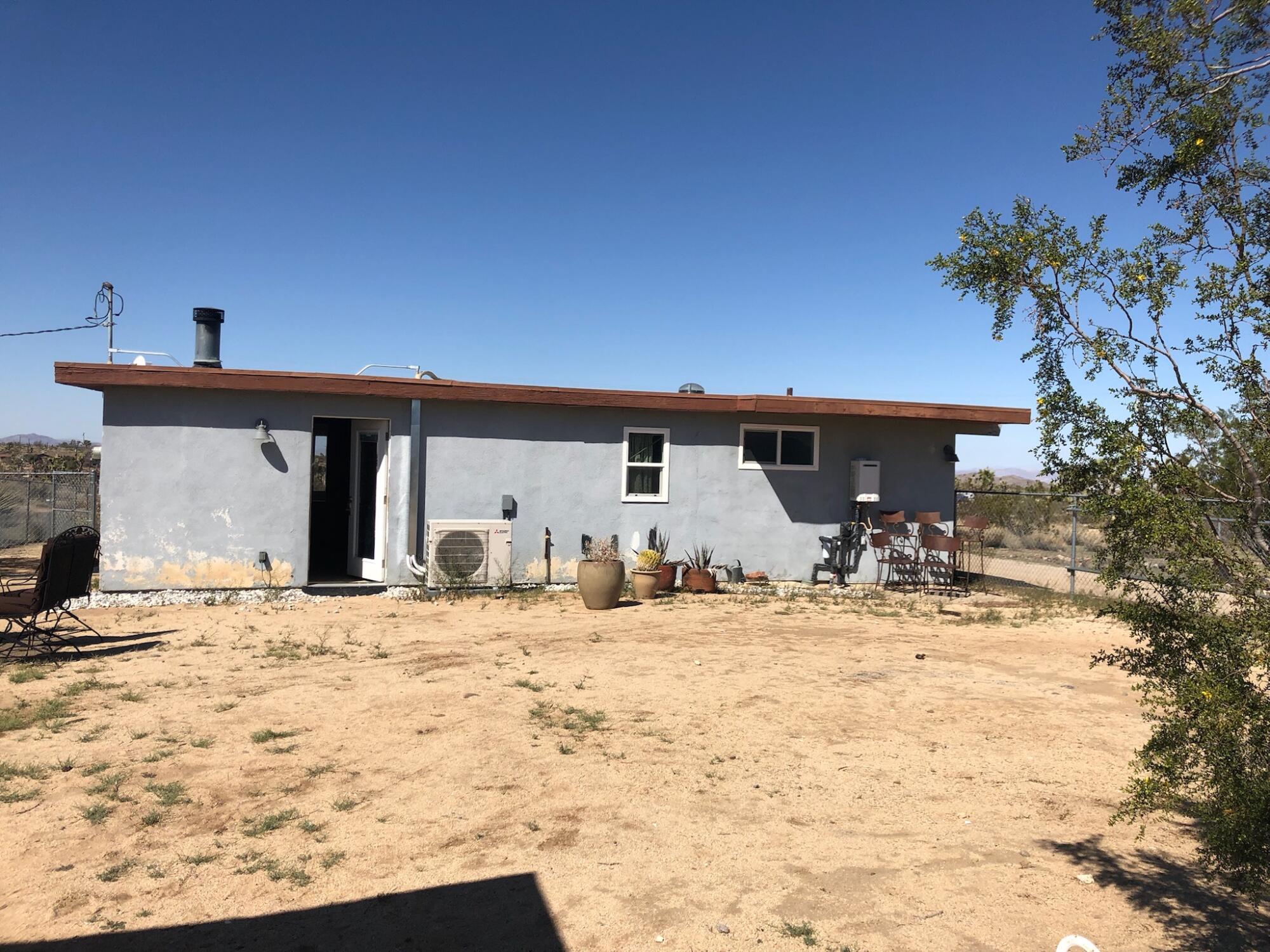 A dilapidated light blue house and a desert landscape.