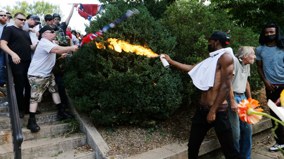 A counterprotester, later identified as Corey Long of Culpeper, Va., uses a lighted spray can against a white nationalist demonstrator at the entrance to Lee Park in Charlottesville in a photo that went viral.