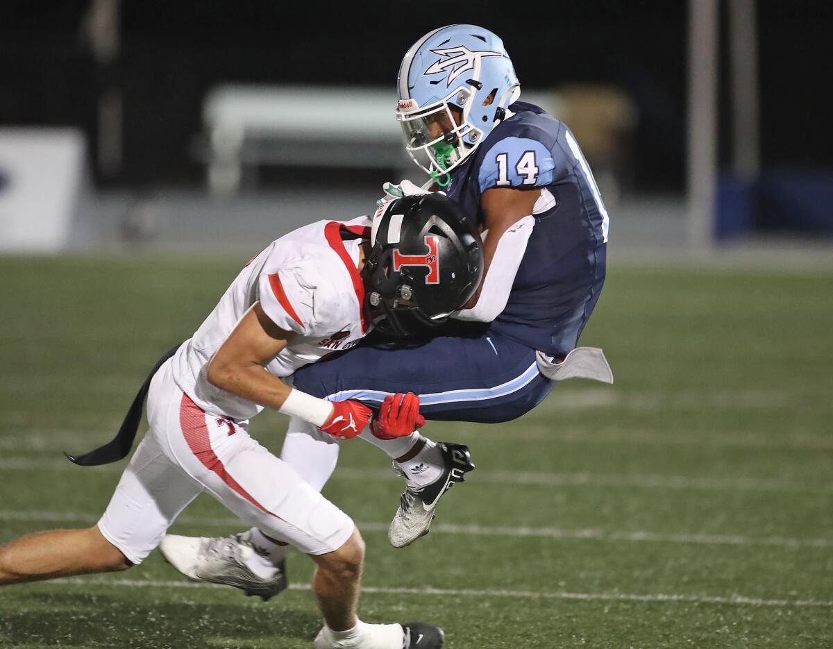 Corona del Mar receiver Emori Davis (14) is tackled after a catch by Riley Kelley during Friday night's nonleague game.