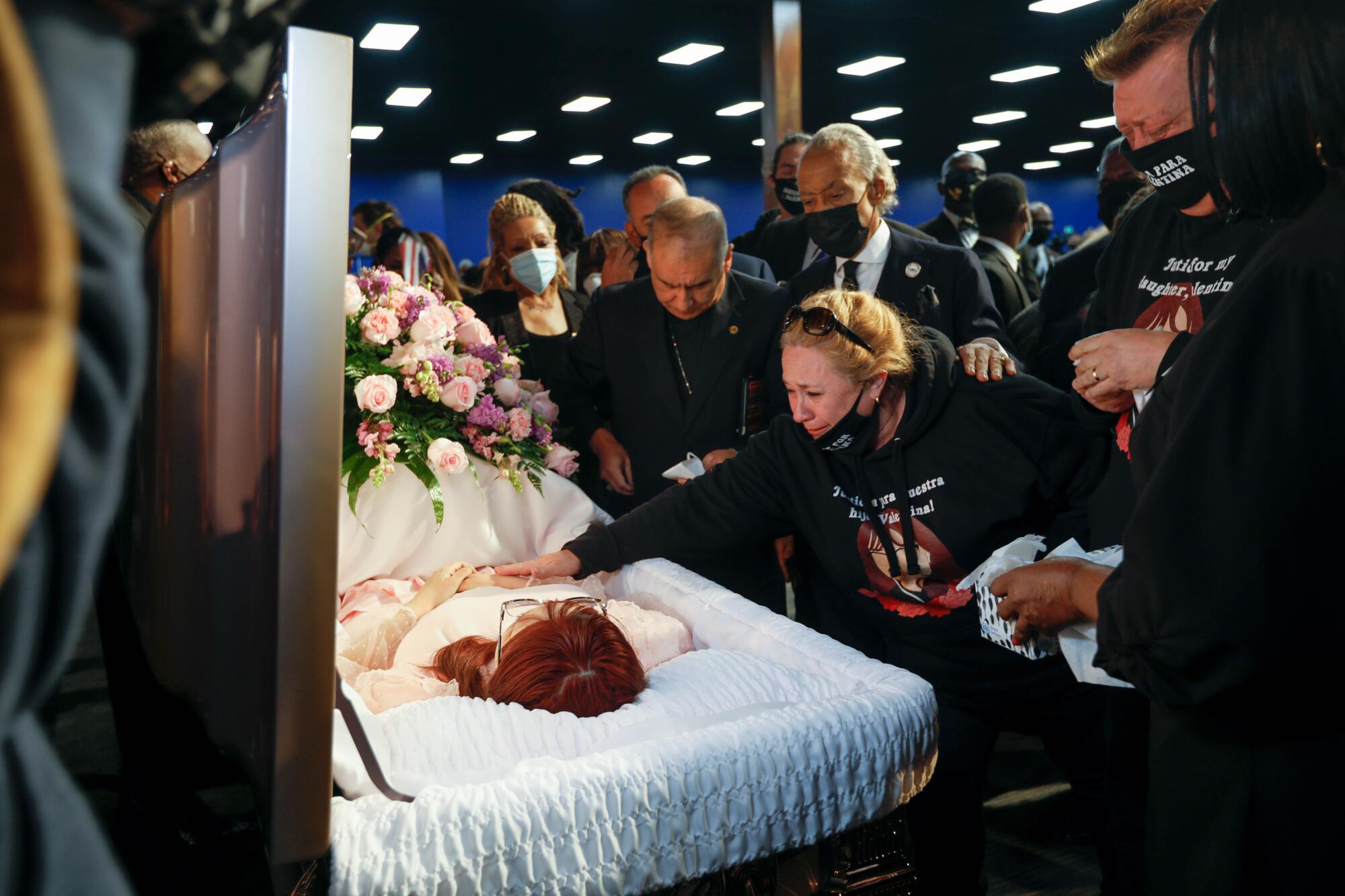 People gather around an open casket