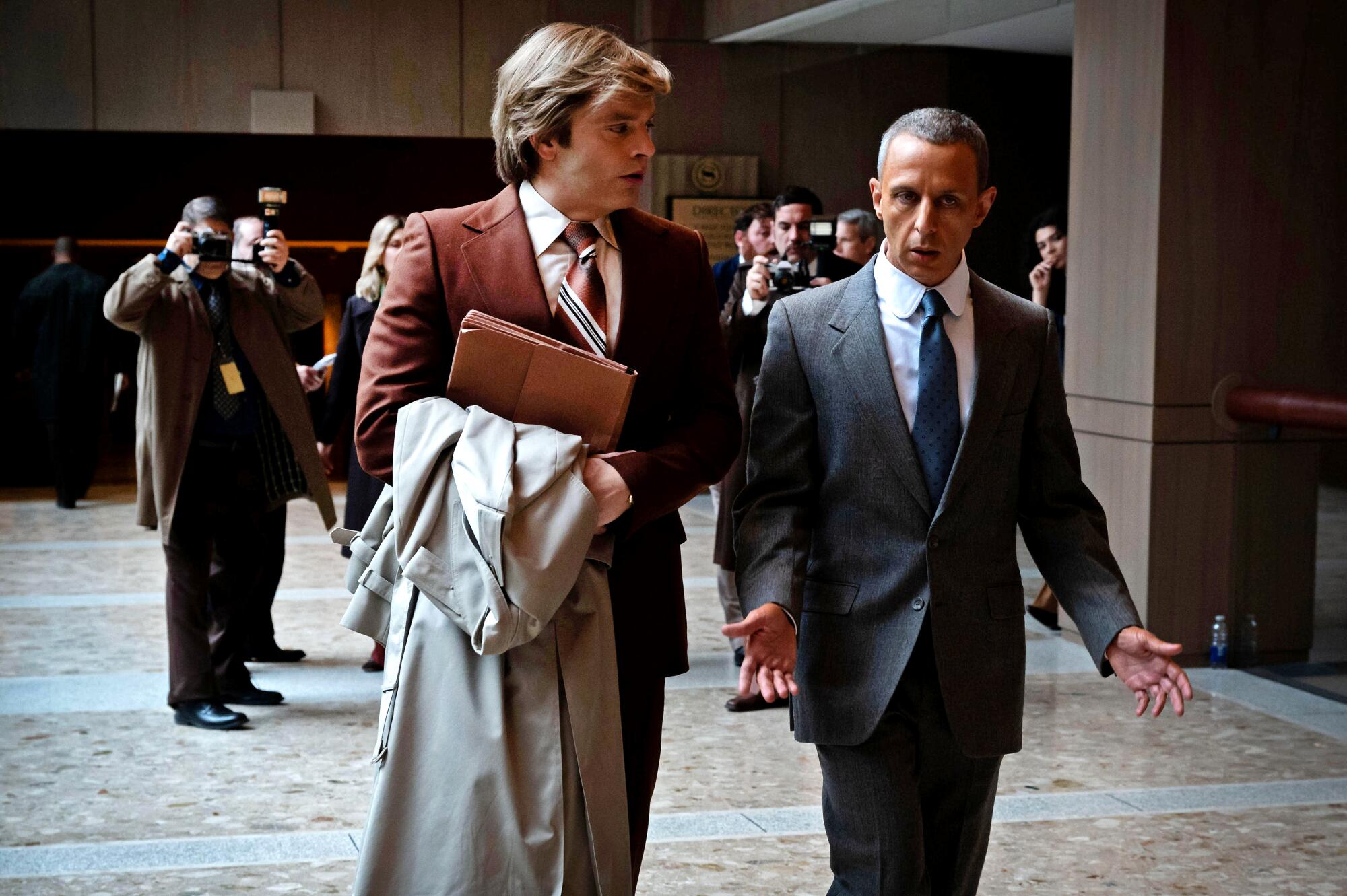 Two men in suits walk and talk in "The Apprentice."