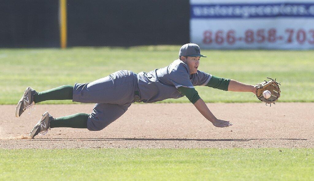 Costa Mesa High third baseman Carter Chapman dives for an infield hit, knocking it down in time for the out at first base against Estancia.
