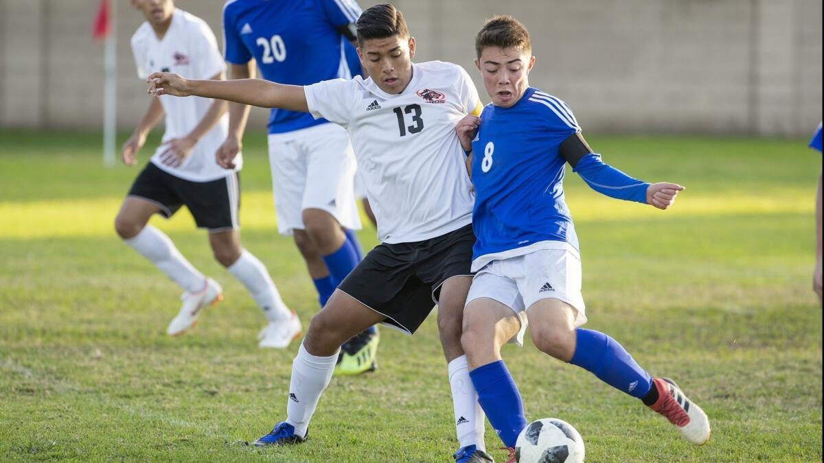 Los Amigos High's Alfonso Montano (13) battles for a ball against La Quinta's Ken Hatfield during a Garden Grove League opener on Tuesday.