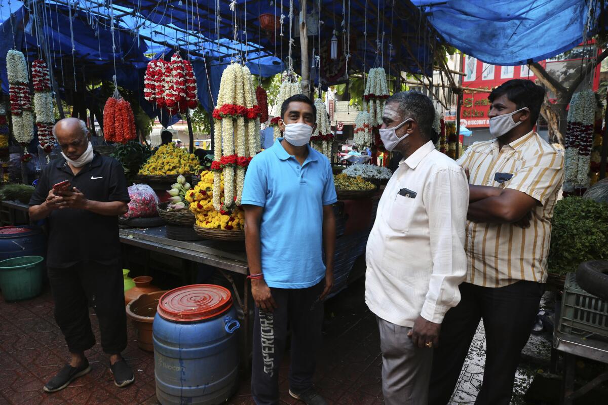 Indians wait outside a popular eatery for their takeaway food orders in Bengaluru, India amid reopening