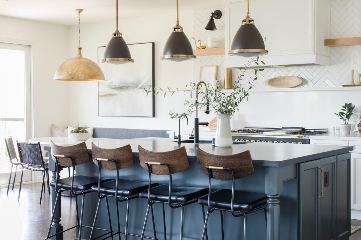 The island cabinets were painted charcoal and matched with an almost 8-foot Black Mist honed slab. Hanging above the island are mixed-metal Schoolhouse pendants in antique brass bronze.