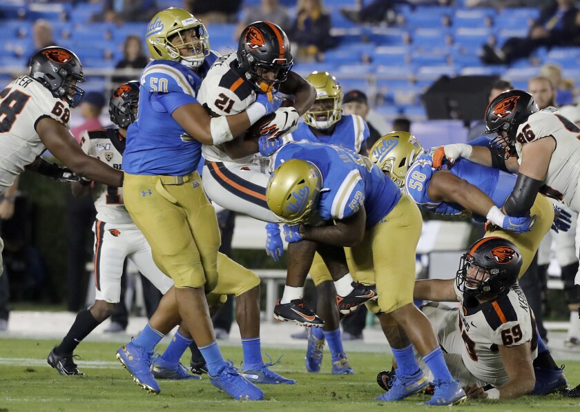 UCLA's Tyler Manoa, left, and Winston Polite bring down Oregon State running back Nahshon Wright.