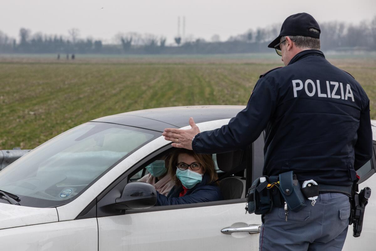 CASALPUSTERLENGO, ITALY - FEBRUARY 23: An Italian National Police officer talks to a driver in a car, wearing a respiratory mask, on February 23, 2020 in Casalpusterlengo, south-west Milan, Italy. Casalpusterlengo is one of the ten small towns placed under lockdown earlier this morning as a second death from coronavirus sparked fears throughout the Lombardy region. (Photo by Emanuele Cremaschi/Getty Images) ** OUTS - ELSENT, FPG, CM - OUTS * NM, PH, VA if sourced by CT, LA or MoD **