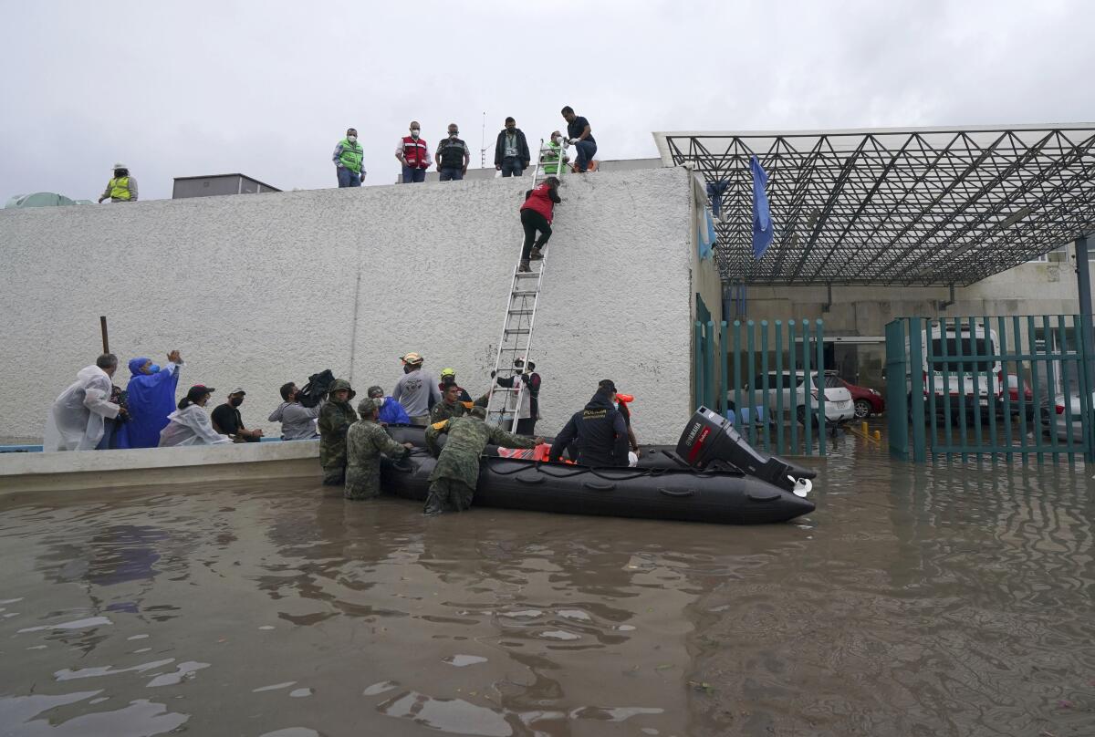 Soldiers rescue health workers on an inflatable boat from a flooded hospital in Tula, Hidalgo state, Mexico, Tuesday, Sept. 7, 2021. Torrential rains in central Mexico suddenly flooded a hospital in Tula, killing more than a dozen patients, with about 40 other surviving as waters rose swiftly and flooded the public hospital. (AP Photo/Marco Ugarte)