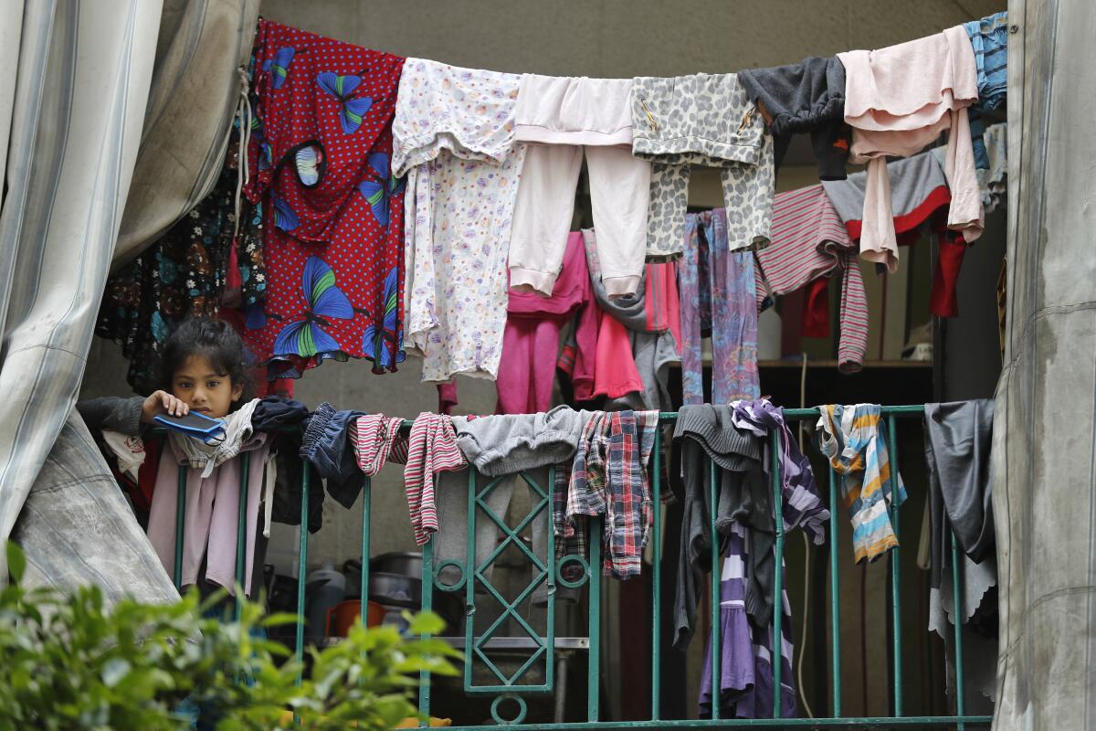 In Beirut, a Syrian girl holds her coronavirus mask at a building crowded with foreign workers. 