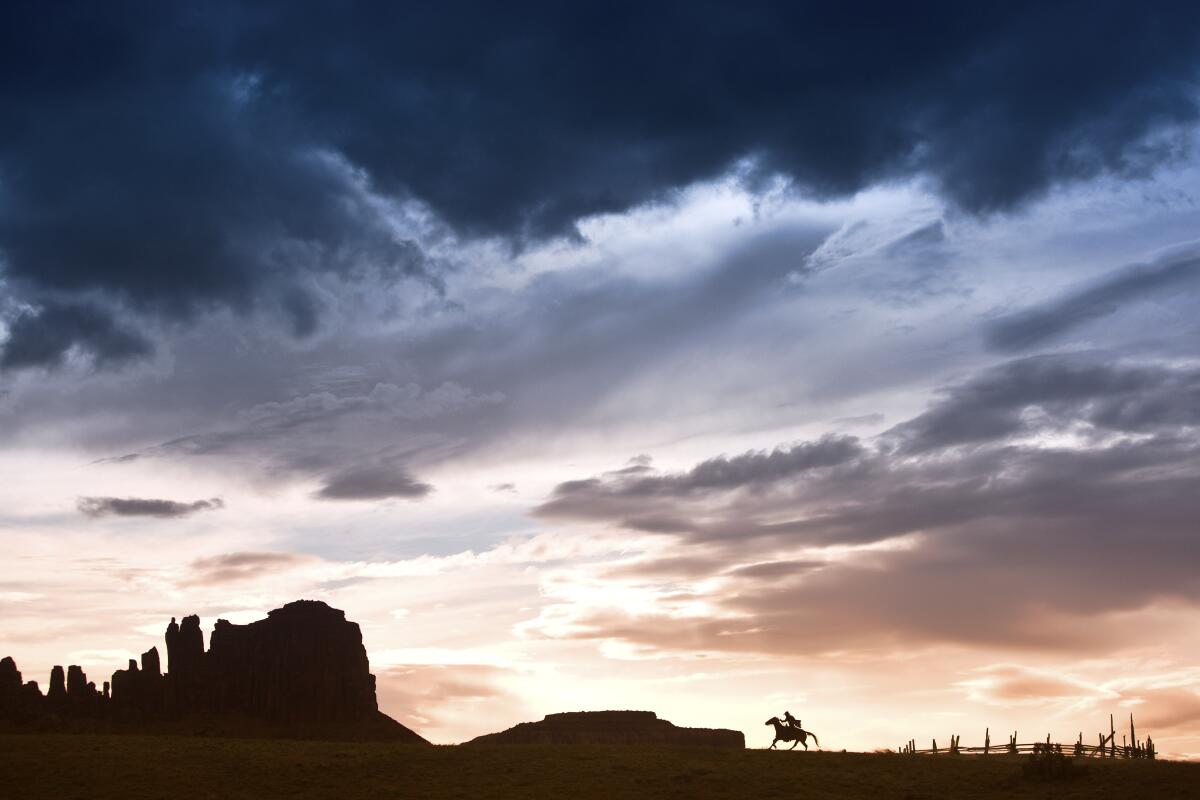 Jim Krantz's "Epic Western No. 7" shows, from far away,  a silhouette of a horse and rider amid rock formations.