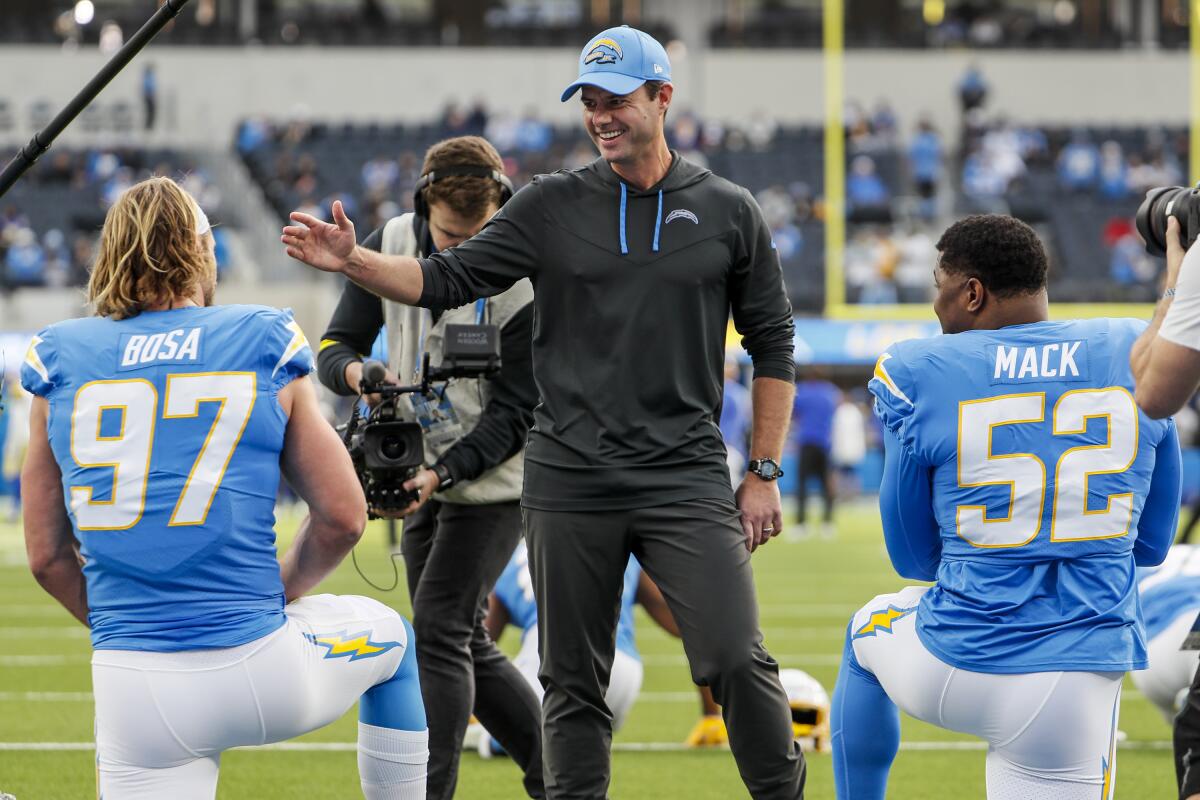 Chargers coach Brandon Staley smiles as he greets Joey Bosa (97) and Khalil Mack before a game.