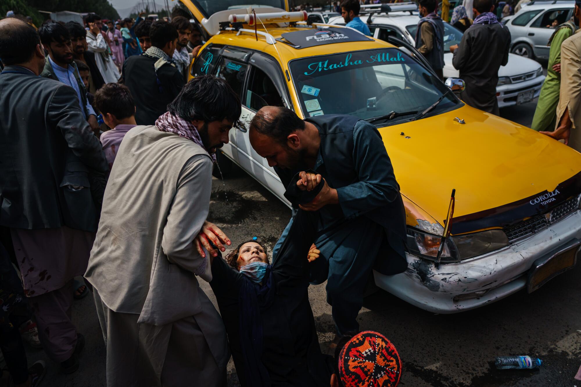 Men try to help a wounded woman to her feet