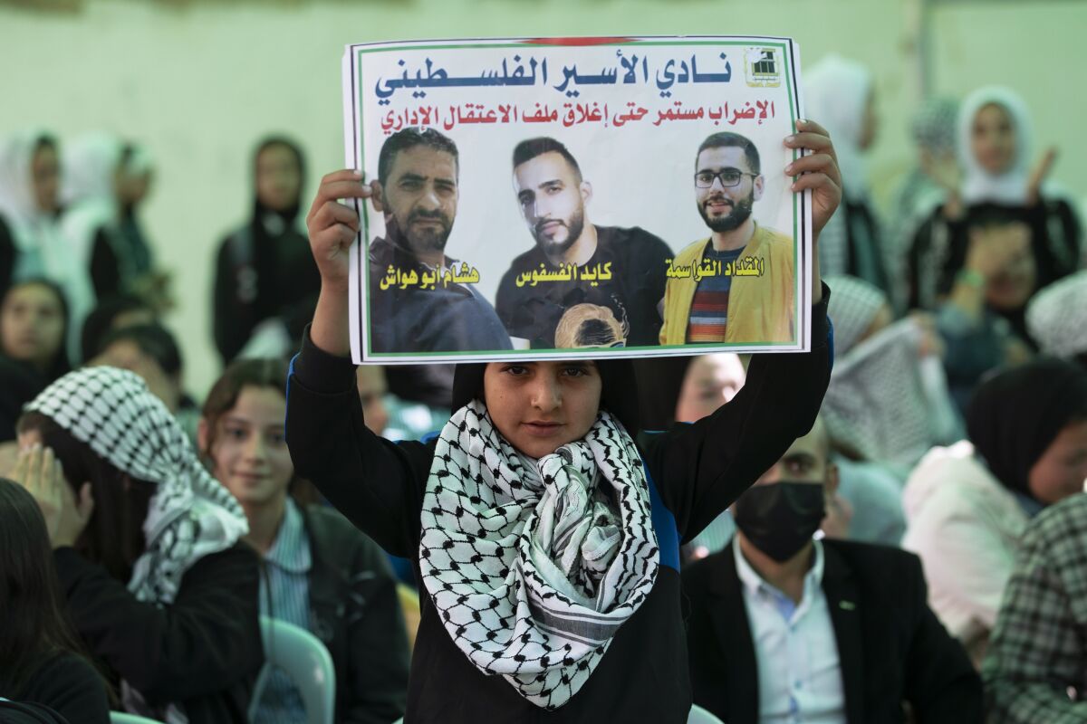 Protesters carry posters showing Kayed Fasfous, a Palestinian prisoner who has been on hunger strike for 120 days to protest being detained without charge by Israel, in the village of ad-Dhahiriya, near the West Bank town of Hebron, Thursday, Nov. 11, 2021. Israel faced growing calls on Thursday to release five Palestinians who have been on hunger strike for weeks to protest a controversial policy of holding them indefinitely without charge. Arabic on poster reads "Freedom for prisoners who are on hunger strike". (AP Photo/Majdi Mohammed)