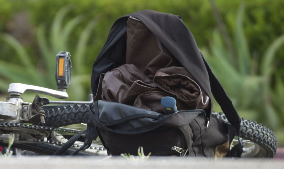 A bicycle and backpack lay in the street on West Laurel Street where a man was taken in to custody in connection with a series of attacks on homeless people. — John Gibbins / San Diego Union-Tribune