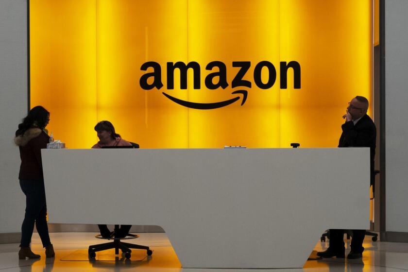 FILE - In this Feb. 14, 2019 file photo, people stand in the lobby for Amazon offices in New York. Amazon.com Inc. reports earns on Thursday, April 25. (AP Photo/Mark Lennihan, File)