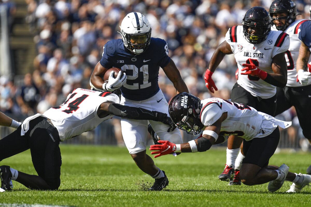 Penn State running back Noah Cain (21) splits two Ball State defenders on a first half run during an NCAA college football game in State College, Pa., on Saturday, Sept. 11, 2021. Penn State defeated Ball State 44-13. (AP Photo/Barry Reeger)