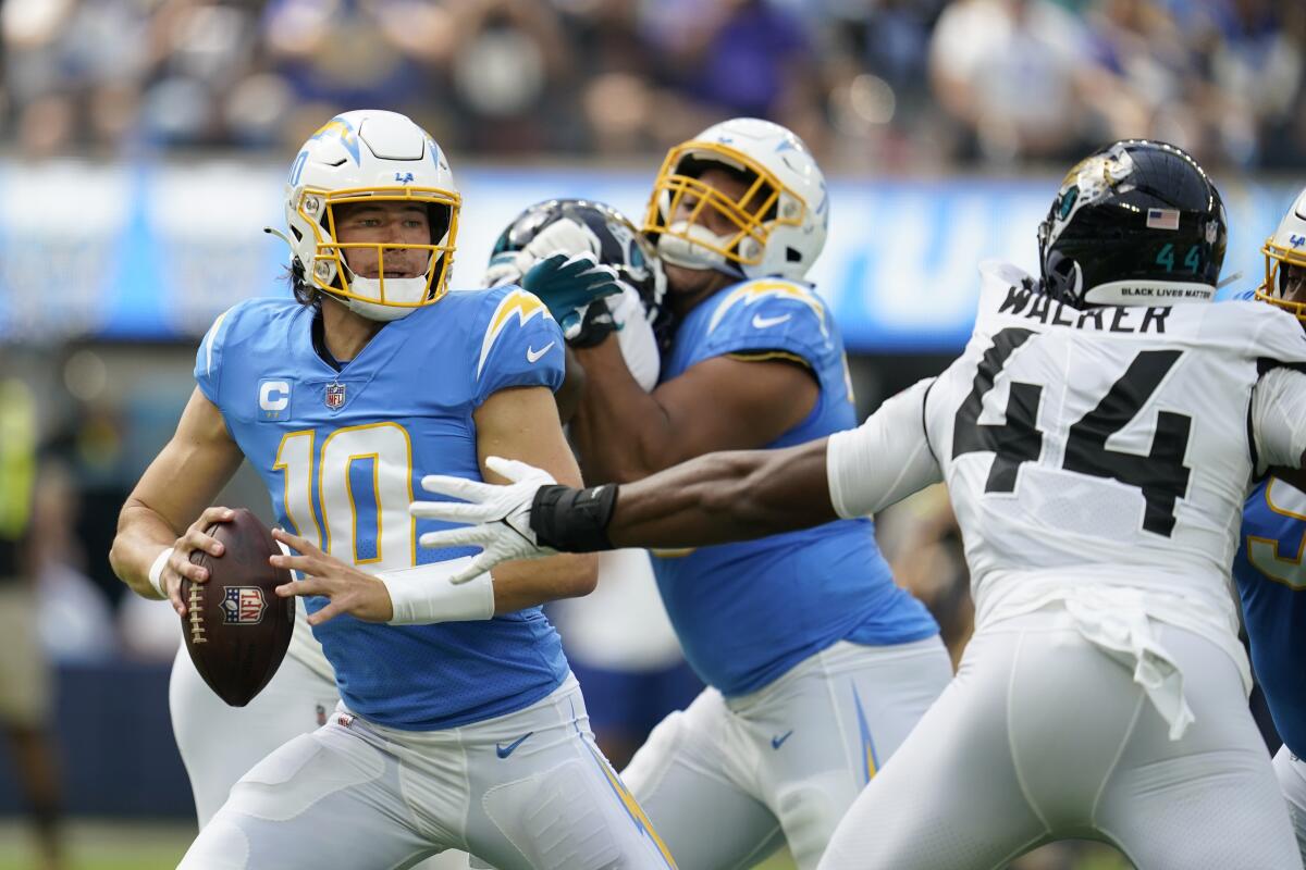 Chargers quarterback Justin Herbert (10) is pressured by Jacksonville Jaguars linebacker Travon Walker.