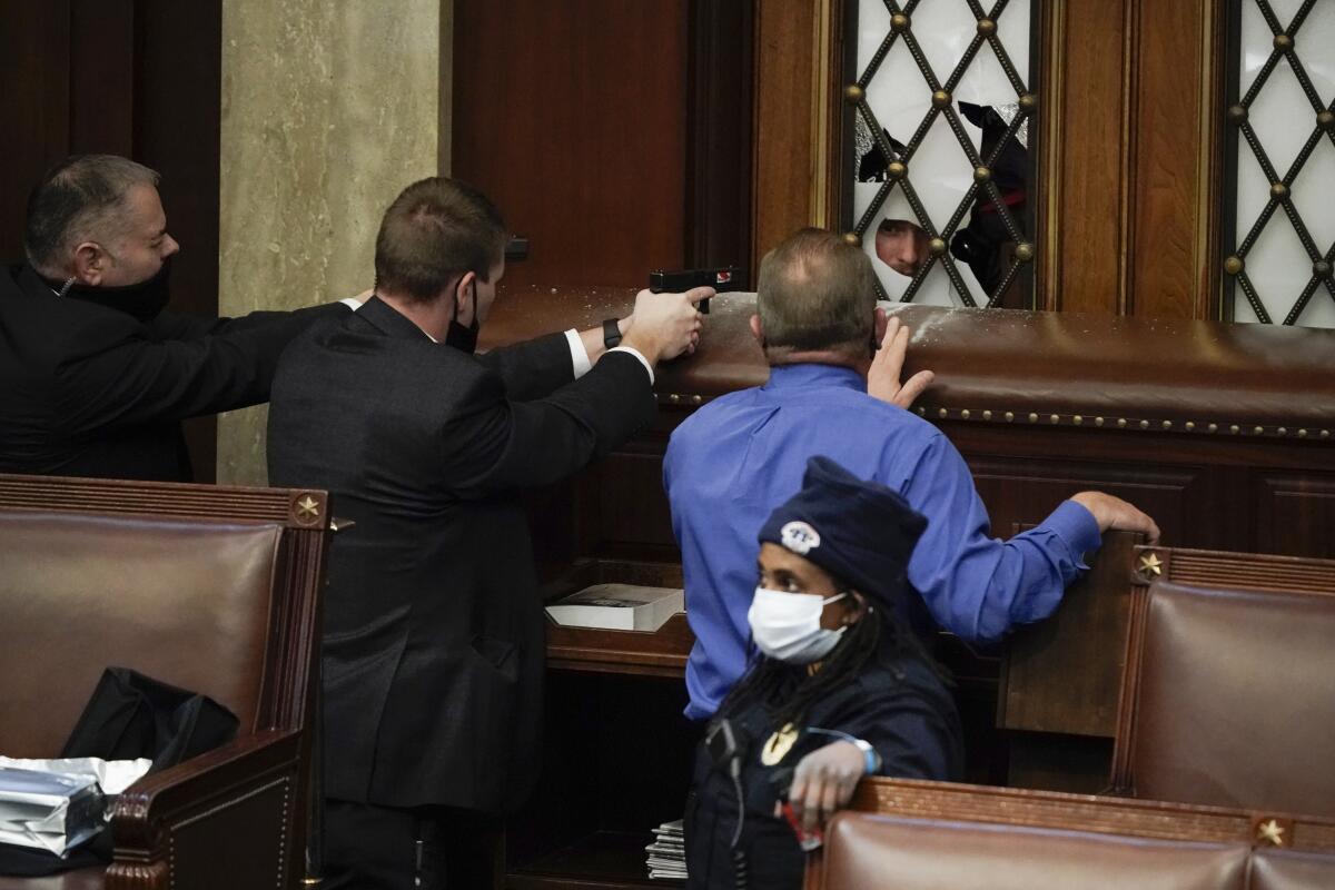 Police, two with guns drawn, standing guard as rioters try to break into the House chamber at the U.S. Capitol 