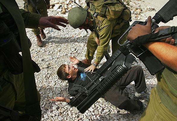 Israeli soldiers scuffle with an Israeli activist today during a demonstration against construction of a barrier near the West Bank village of Maasarah, near Bethlehem. Israel says the barrier, aimed at sealing off the Jewish state from the West Bank, is necessary for security; Palestinians see the move as a unilateral redrawing of the border.