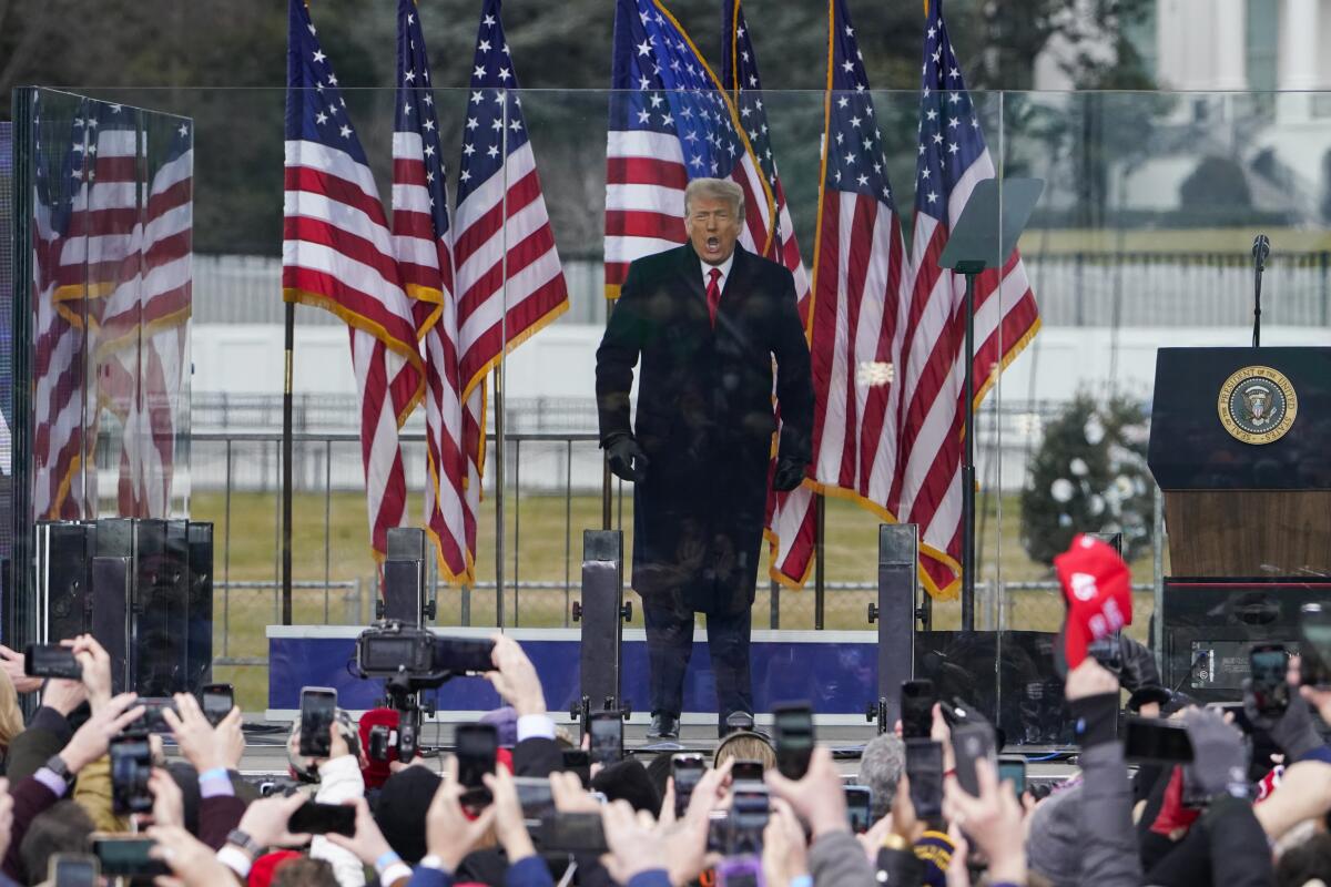 President Trump on outdoor stage in front of flags 