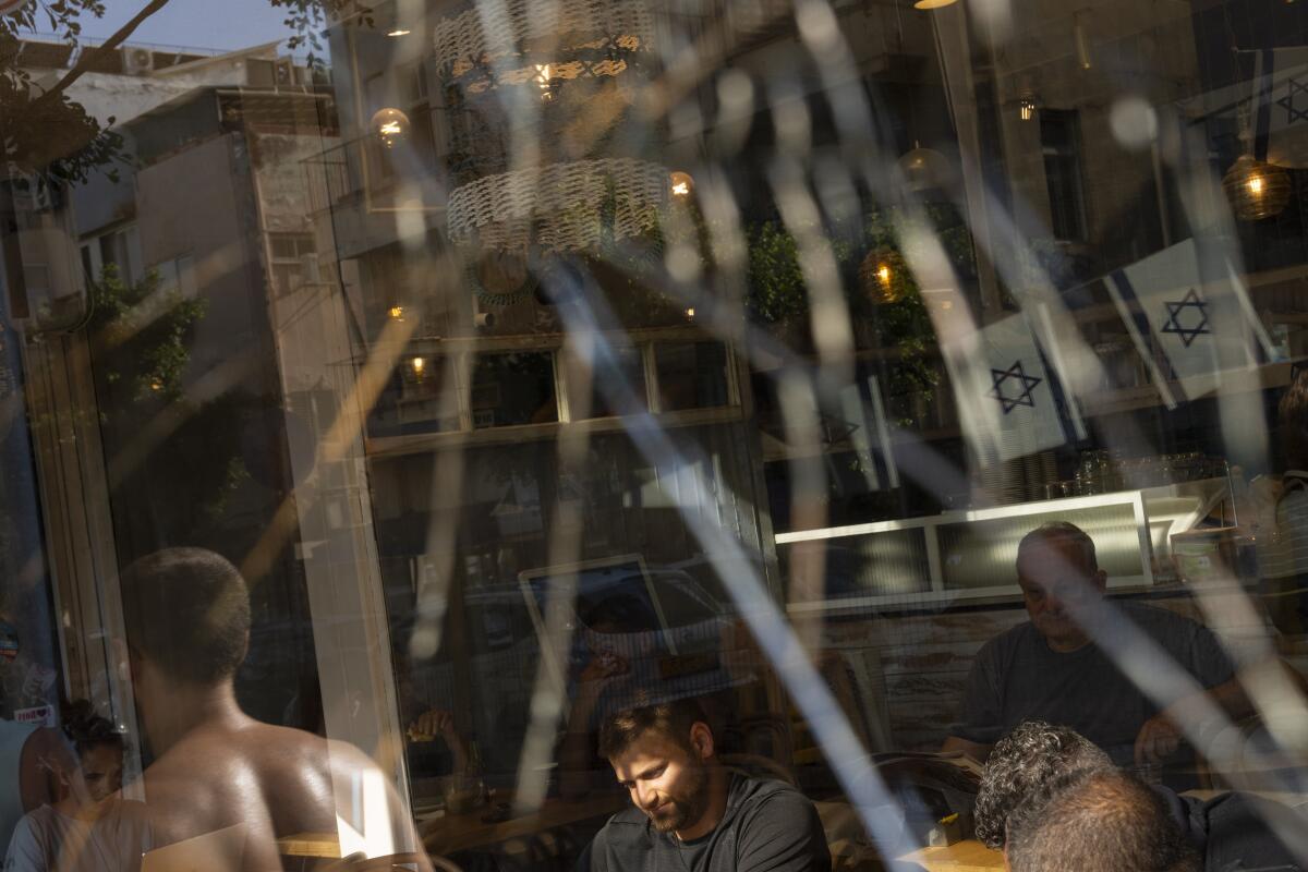 People are seen through a broken coffee shop window.