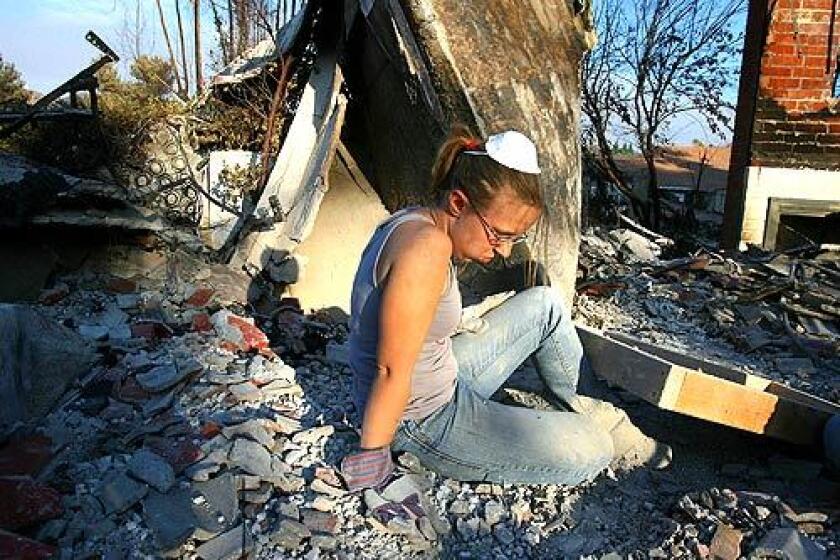 Cassondra Ott, 24, sits amid the debris of her boyfriend's home in Rancho Bernardo, near San Diego. Authorities closed an emergency shelter at San Diego's Qualcomm Stadium and bused the remaining evacuees, only about 115 of the nearly 13,000 once housed there, to the Del Mar Fairgrounds.