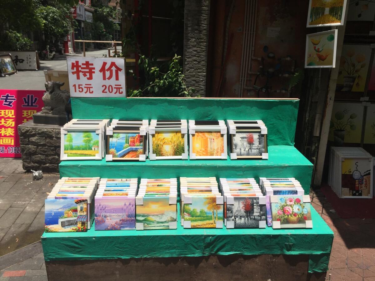 Shown are pictures for sale in Dafen Oil Painting Village in China. The sign says the paintings cost 15 to 20 yuan each, about $2 to $3.