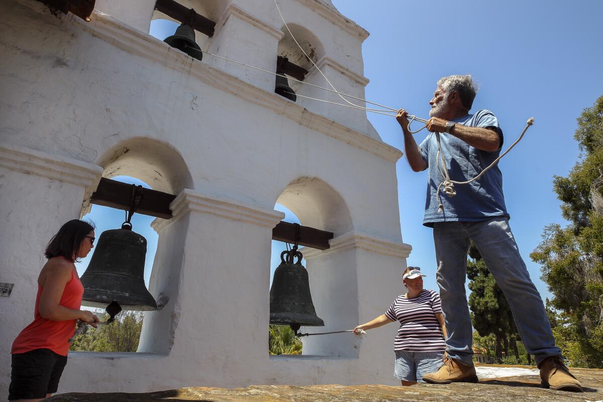 George Lane, right, Crystal Carr, left, and Misty Suposs pull the ropes to ring all five bells at the same time, which is only done once a year, during the annual Festival of the Bells at Mission Basilica San Diego de Alcalá on Saturday.
