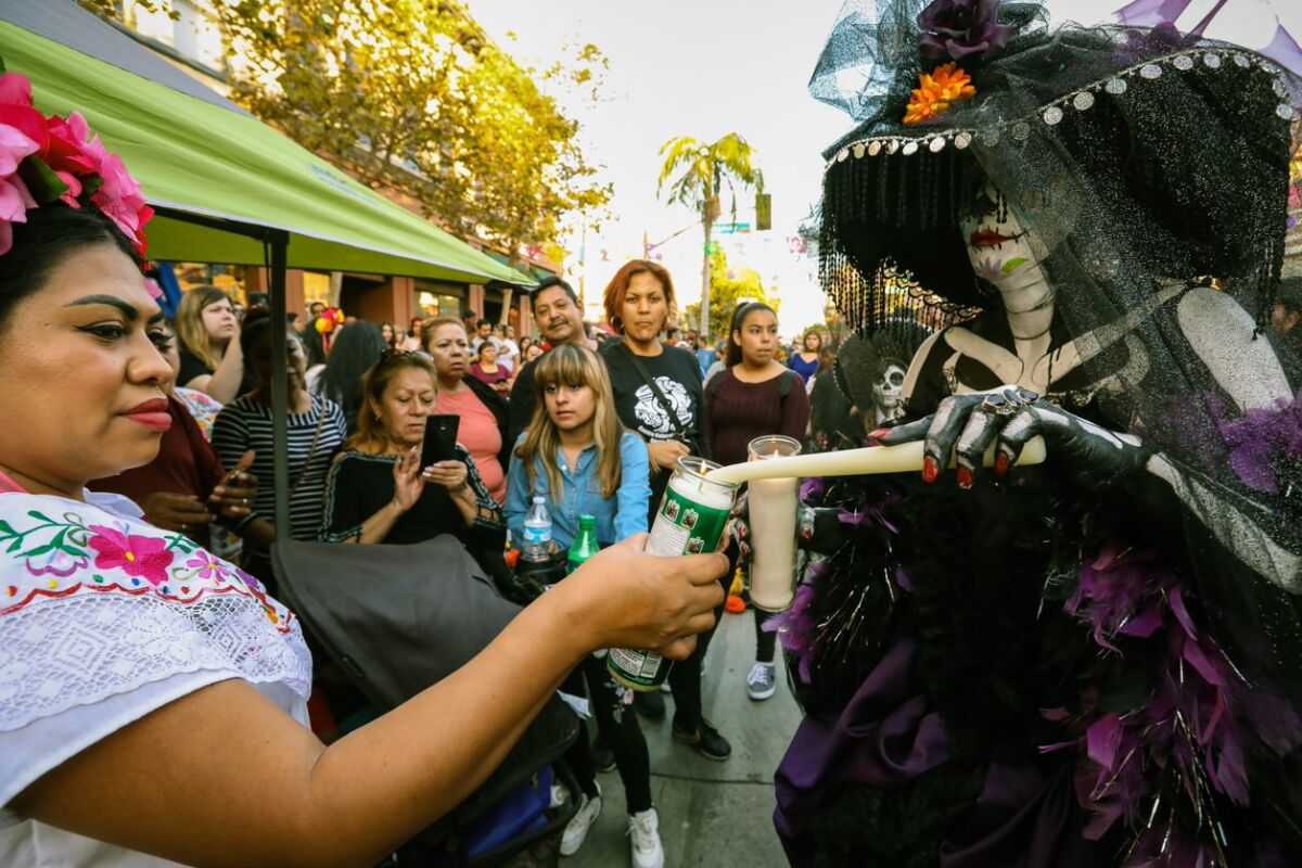 Catrina encendiendo velas en un evento anterior de Noche de Altares en Santa Ana.