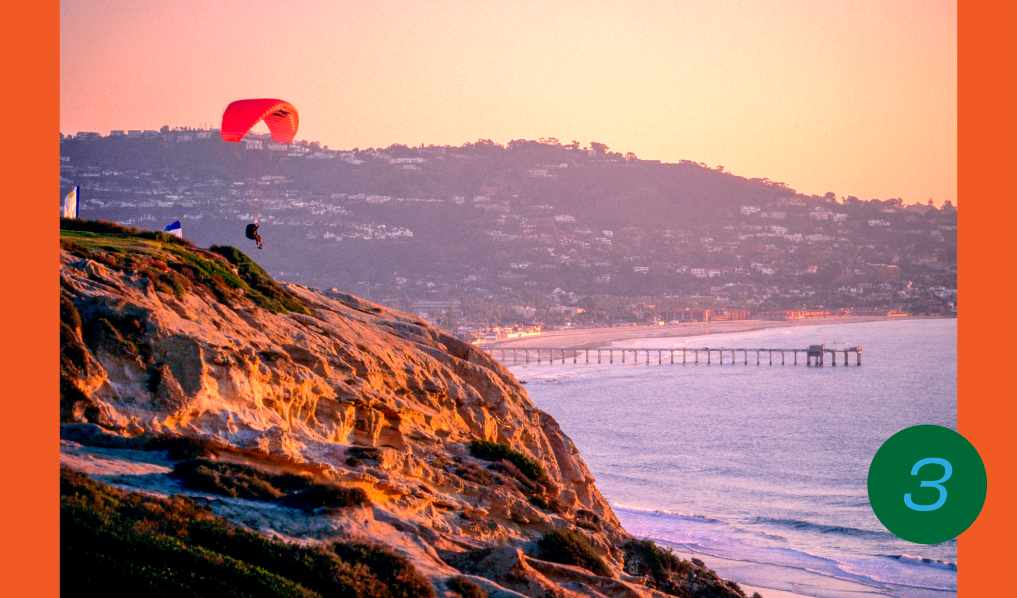 A hang glider soars above an oceanfront cliff at sunset at the Torrey Pines Gliderport 