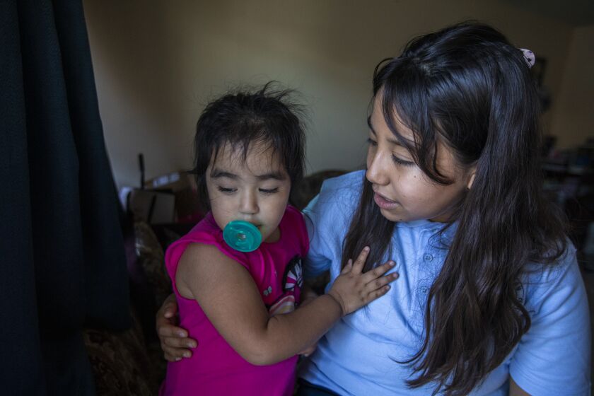 East Los Angeles, CA - August 10: Portrait of Ruby Marquez, age 2, left, with her sister Esmeralda Marquez, 11, at their home on Wednesday, Aug. 10, 2022, in East Los Angeles, CA. Esmeralda will be attending sixth grade this year. Esmeralda says she deals with anxiety when she is around others not wearing masks in public during the pandemic. Ruby, her younger sister was born prematurely and spent months in the hospital. Esmeralda explains she needs to be cautious to protect her sister who still deals with health issues. (Francine Orr / Los Angeles Times)