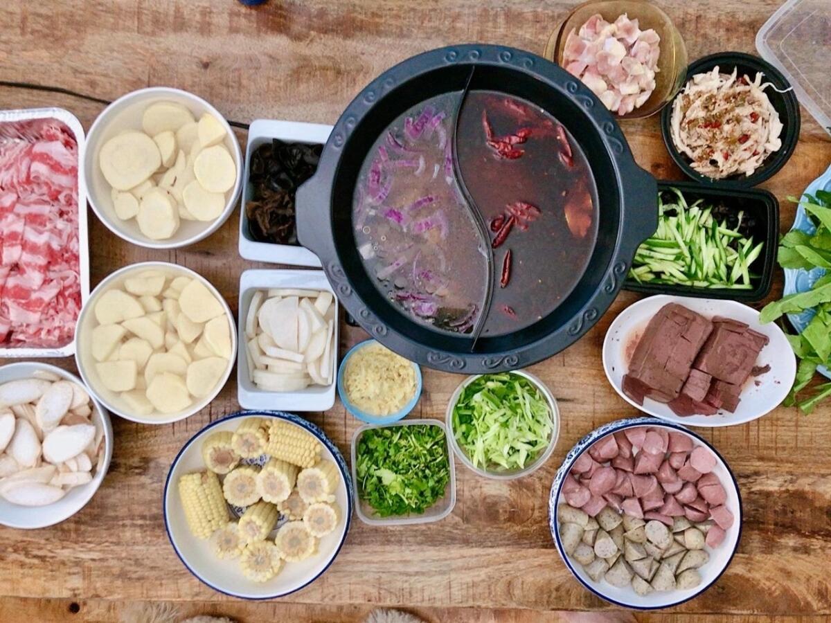 The left side of a divided hot pot contains a mild chicken-based broth, while the right side is a spicy pork-based broth.
