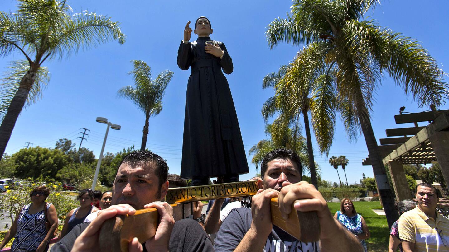 Jose Ochoa, left, and Jairo Moran carry the statue of Santo Toribio Romo Gonzalez during a procession to the chapel at Santiago de Compostela Catholic Church in Lake Forest.