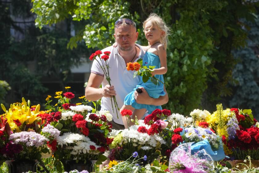 People lay flowers for the victims of the Russian rocket attack at a shopping center in Kremenchuk, Ukraine, Wednesday, June 29, 2022. (AP Photo/Efrem Lukatsky)