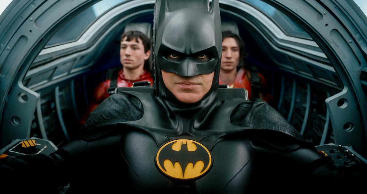 Michael Keaton, center, plays Batman, with Ezra Miller as two versions of Barry Allen/the Flash, in the movie "The Flash."