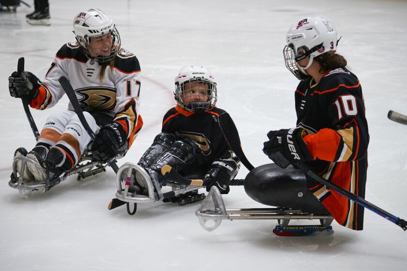 POWAY, CA - JULY 30: Sarah Bettencourt, left, founder of San Diego Ducks Sled Hockey, and Paralympian Lera Doederlein, right, work with Andrew Kane, 5, center, of Tierrasanta, who has spina bifida, during the Try Sled Hockey clinic held at The Rinks-Poway Ice, Saturday July 30, 2022 and hosted by the team. (Howard Lipin / For The San Diego Union-Tribune)