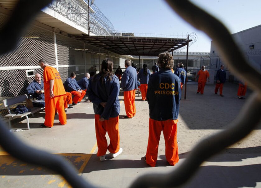Inmates walk around a recreation yard at the Deuel Vocational Institution in Tracy, Calif.