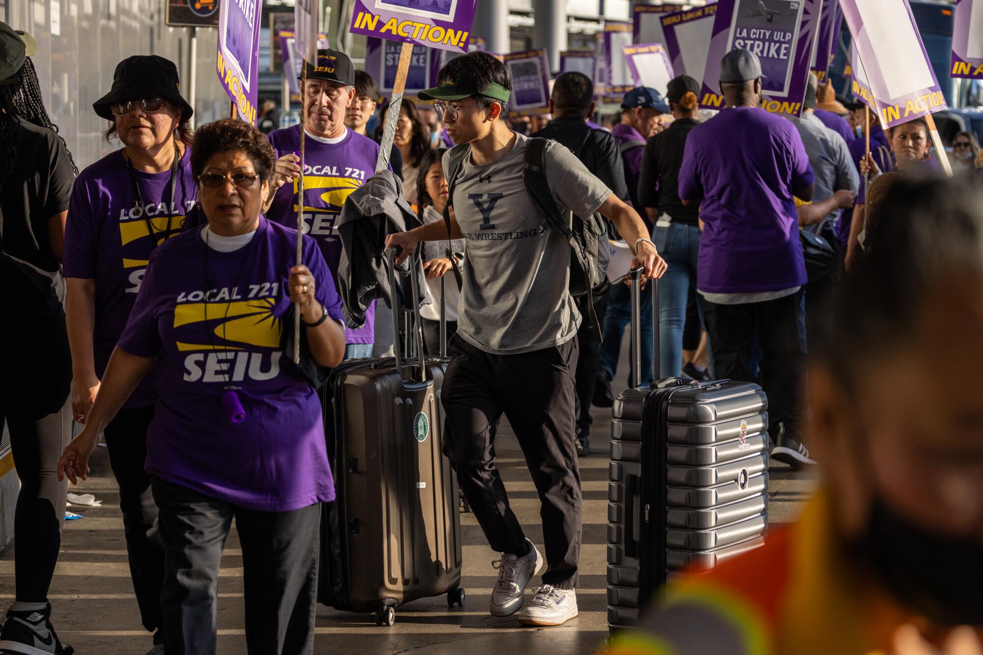Passengers on the way to a departing terminal negotiate through scores of Los Angeles city workers picketing at LAX.