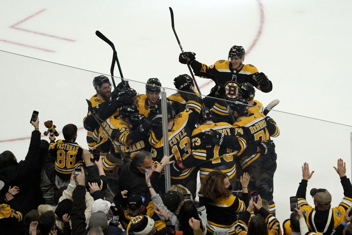 Boston Bruins center Charlie Coyle (13) is congratulated by teammates after scoring the game-winning goal in overtime during an NHL hockey game against the Buffalo Sabres, Saturday, Jan. 1, 2022, in Boston. (AP Photo/Mary Schwalm)