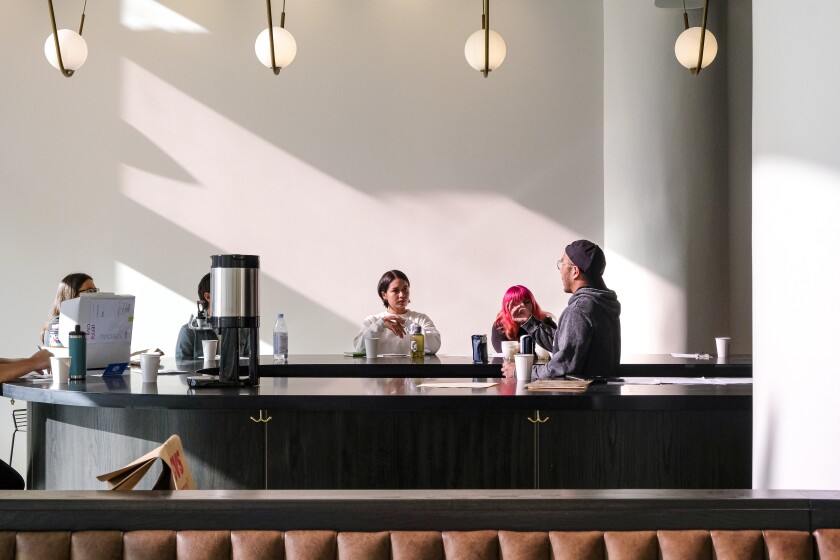 A photo of a few people seated at a minimalist coffee bar