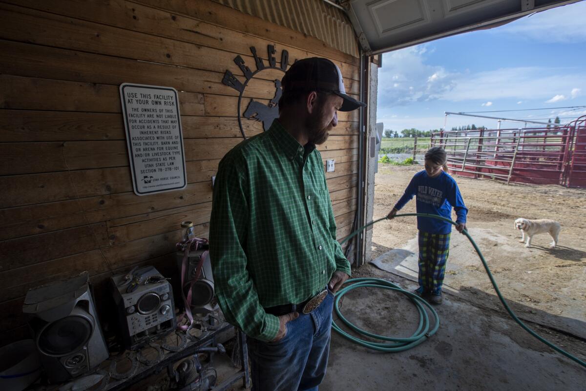 Nathan Ivie, left, watches as his daughter McKiley, 11, coils up a hose after watering horses on the family's ranch. (Brian van der Brug / Los Angles Times)