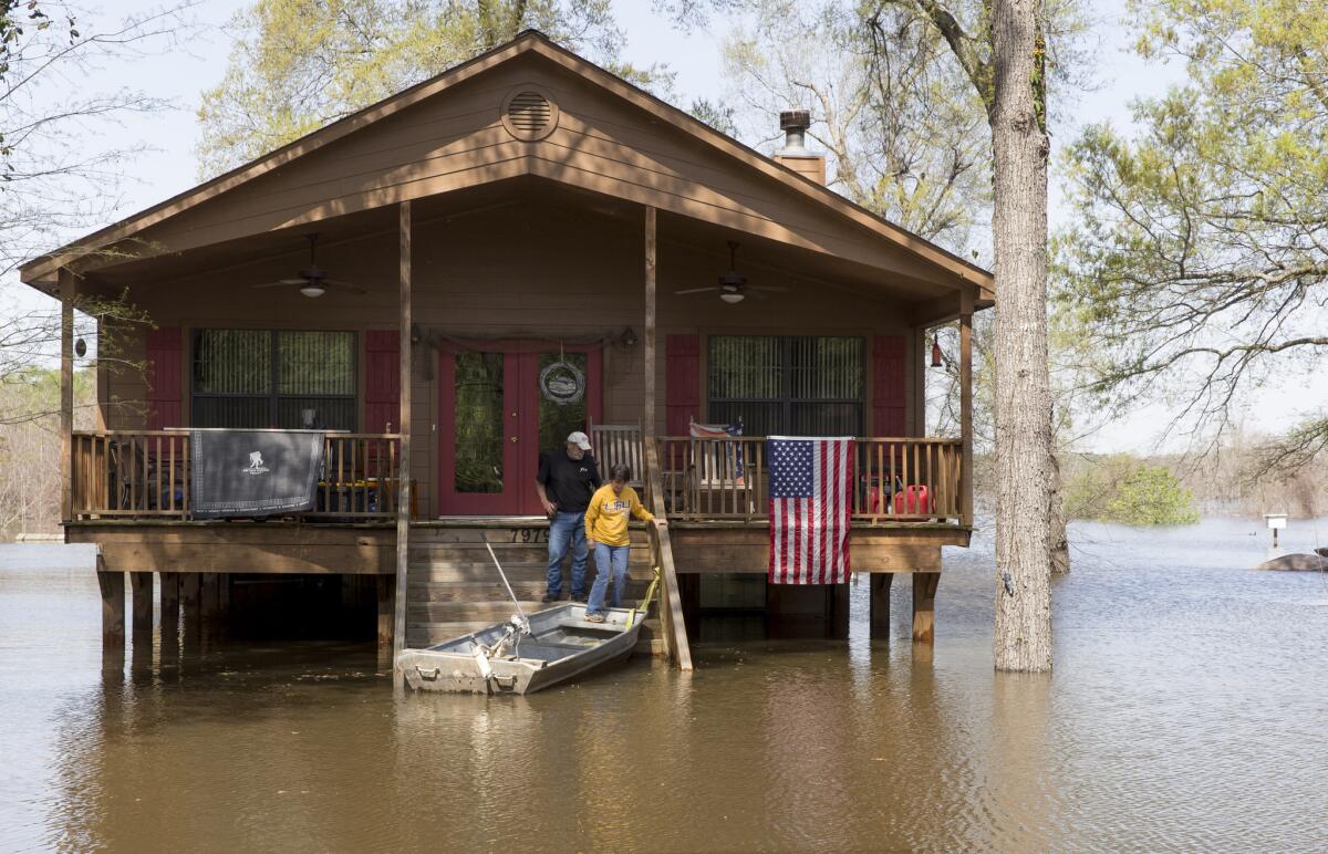 Residents make their way to a boat as water from Caddo Lake surrounds a raised house in Mooringsport, La.