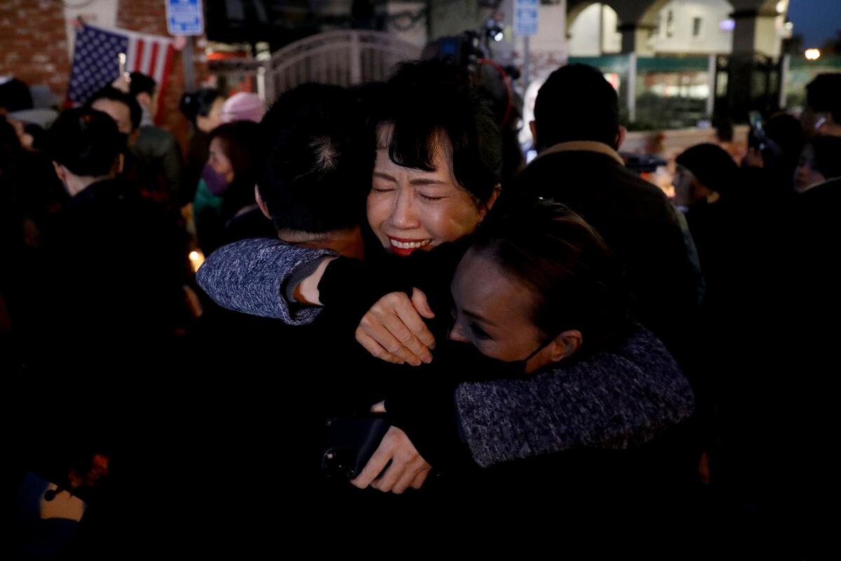 A woman hugs two others while visiting the site of the shooting 
