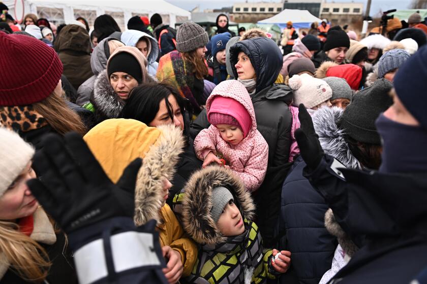 Medyka, Poland March 8, 2022: Anxious Ukrainian refugees start push towards a bus as a police officer advises them to back at the border in Medyka, Poland Tuesday. (Wally Skalij/Los Angeles Times)