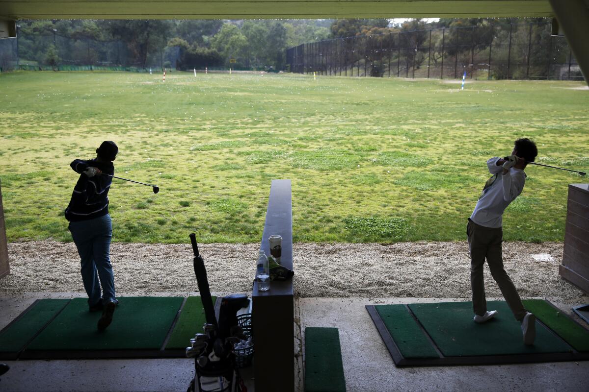 Benjamin Silva, left, and Andre Leonard practice on the driving range at the Wilson and Harding golf courses in Griffith Park on March 19, 2020. Golfing lends itself to social distancing and is giving players a chance to get outside.