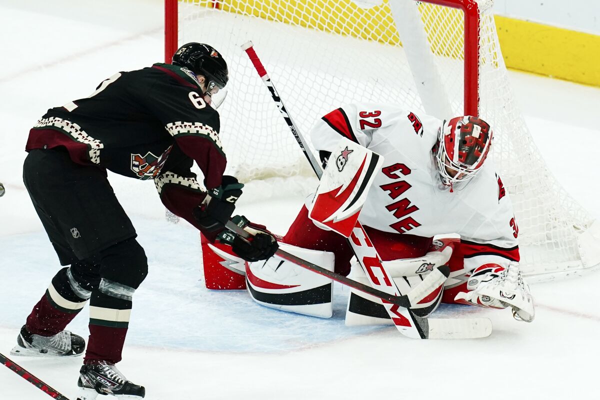 Carolina Hurricanes goaltender Antti Raanta (32) stops a shot by Arizona Coyotes defenseman J.J. Moser, left, during the first period of an NHL hockey game Monday, April 18, 2022, in Glendale, Ariz. (AP Photo/Ross D. Franklin)