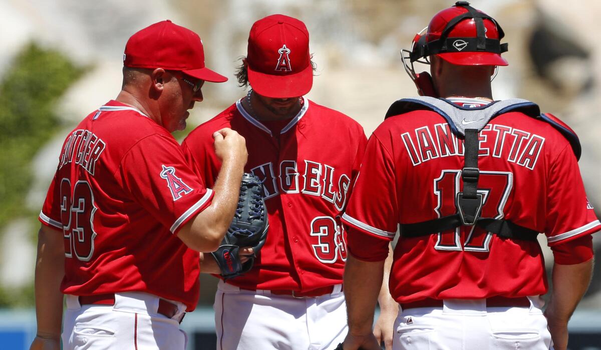 Angels pitching coach Mike Butcher talks to starter C.J. Wilson and catcher Chris Iannetta in the second inning of a 9-2 loss to the Royals on Sunday.