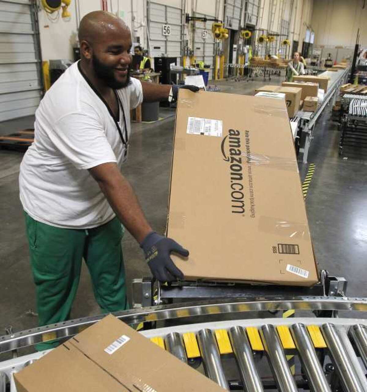 Leacroft Green carries a package to the correct shipping area at an Amazon.com fulfillment center in Goodyear, Ariz. Amazon has just opened two similar facilities in Northern California.